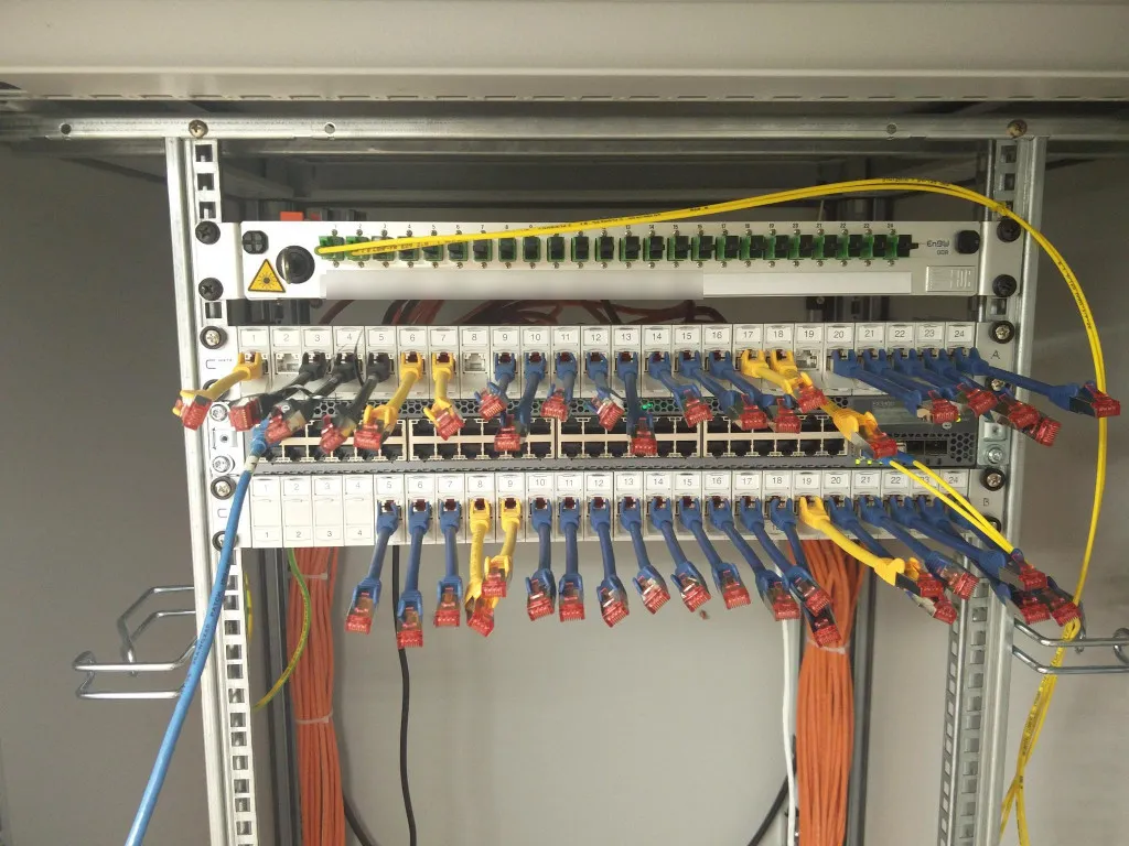 Starting to patch the the copper RJ45 patchcables neatly between patchpanel and switch. // Während des Patchens der RJ45 Kupferkabel zwischen Patchpanel und Switch.