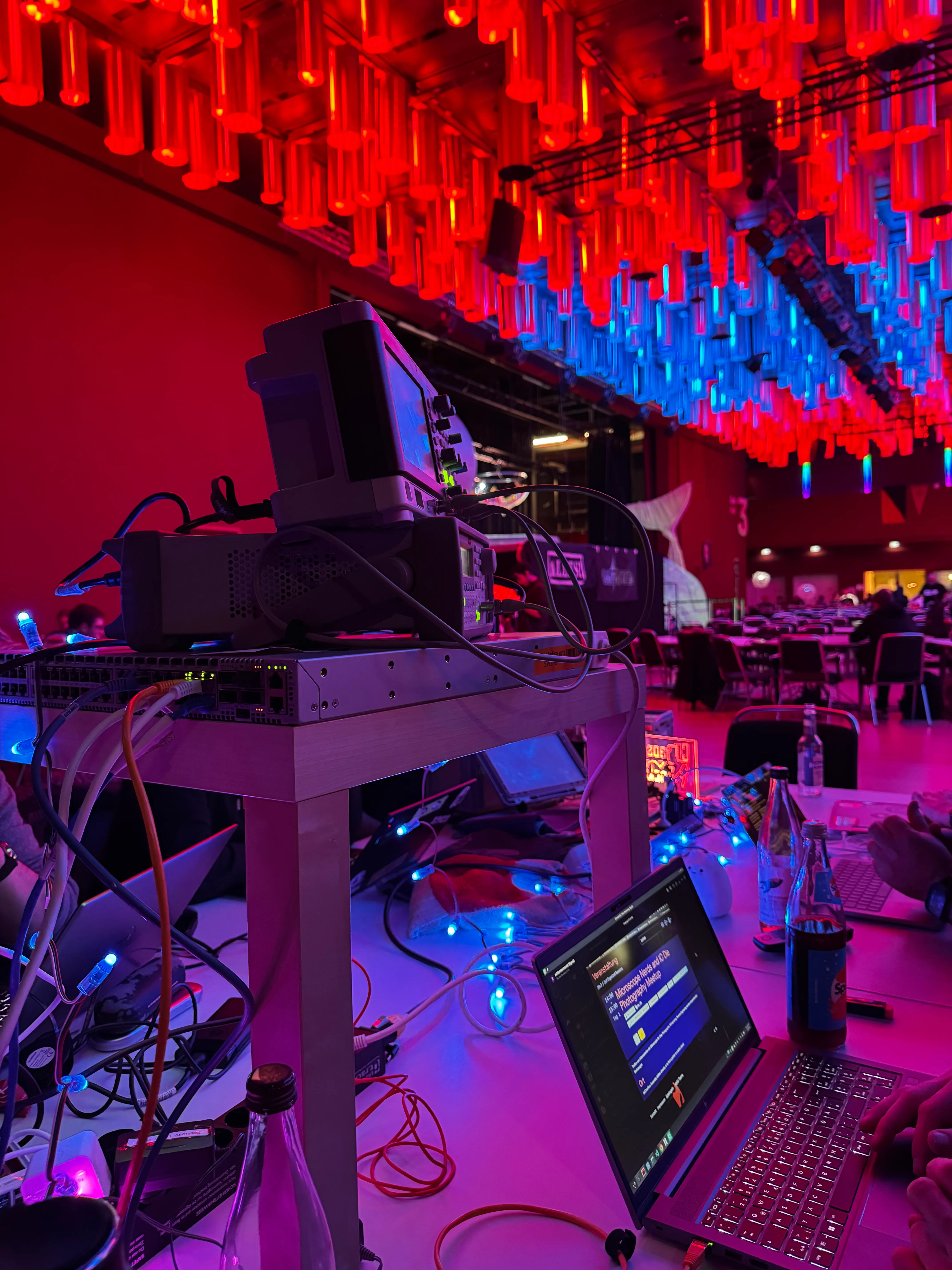 Measurement equipment on a table, a laptop in the foreground, and the ceiling of one of the Chaos Communication Congress halls behind it in the background
