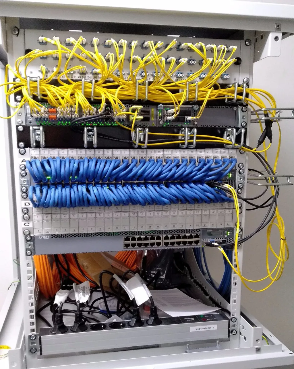 Foto des Core Routers im Studentendorf Ludwigsburg (Juniper EX4600) und 2 Access Switchen (Juniper EX3300) unterhalb eines Glasfaser Patchpanels.